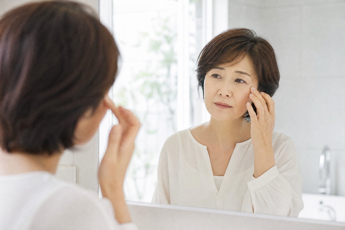 鏡の前で目元にふれる女性