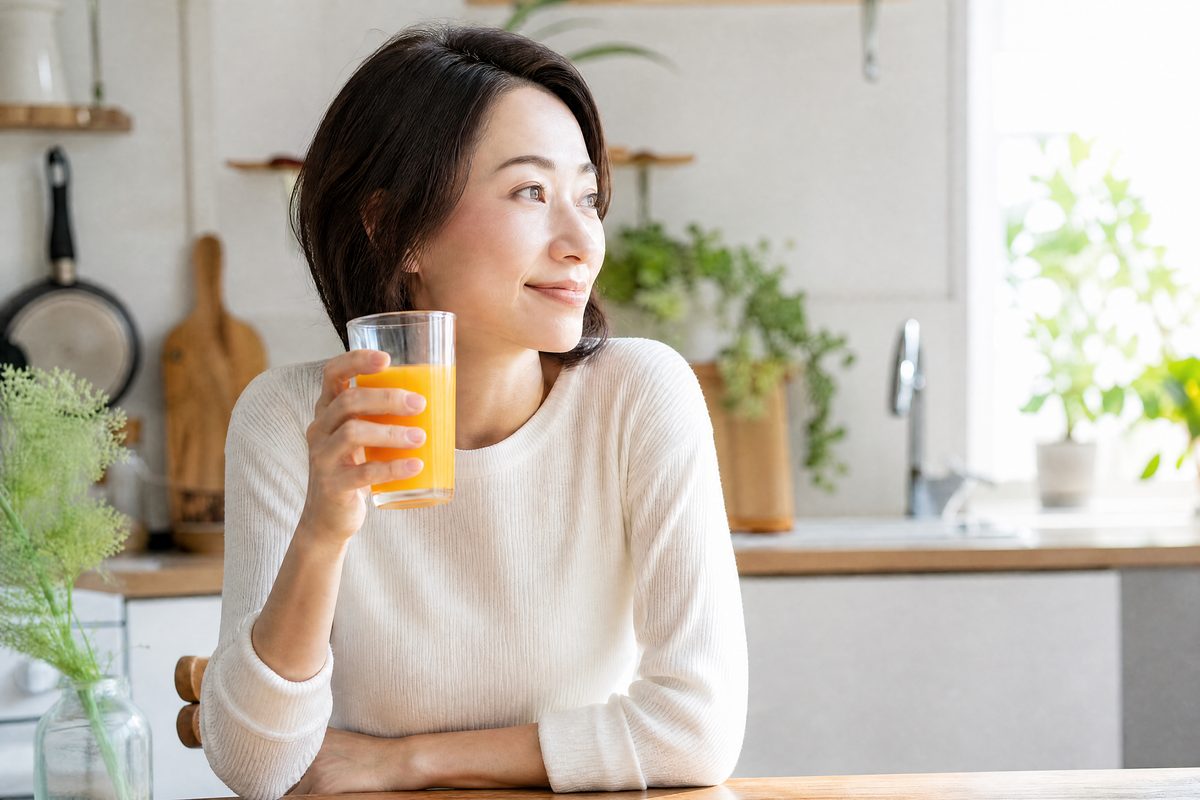 朝のキッチンでグラスを手にひと息つく女性